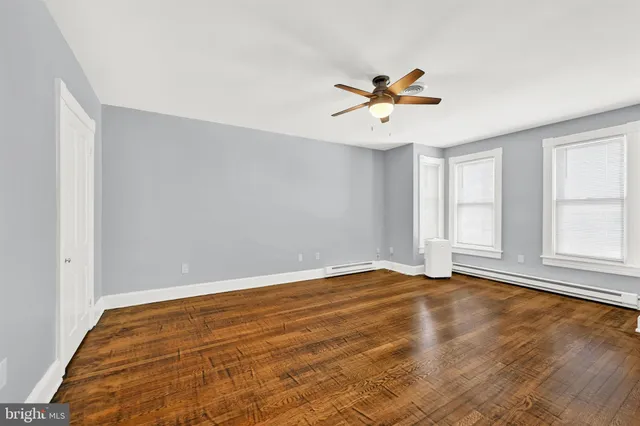 a view of empty room with wooden floor and fan