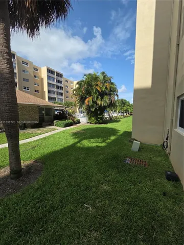 a view of a apartment with a big yard and potted plants