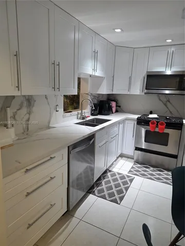 a kitchen with granite countertop a sink stainless steel appliances and cabinets