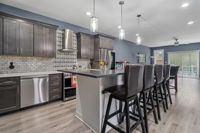 a kitchen with a dining table chairs stainless steel appliances cabinets and wooden floor