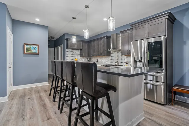 a kitchen with stainless steel appliances kitchen island granite countertop a refrigerator a stove a microwave oven a sink with island and chairs