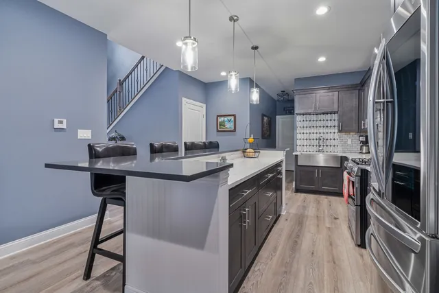 a kitchen with kitchen island a counter top space a sink stainless steel appliances and cabinets