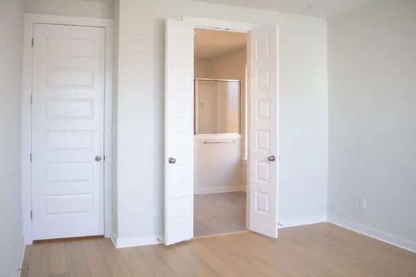 a view of an empty room with a window and wooden floor