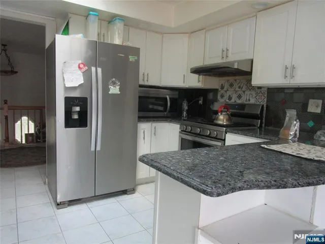 a kitchen with stainless steel appliances granite countertop a refrigerator a stove and a sink