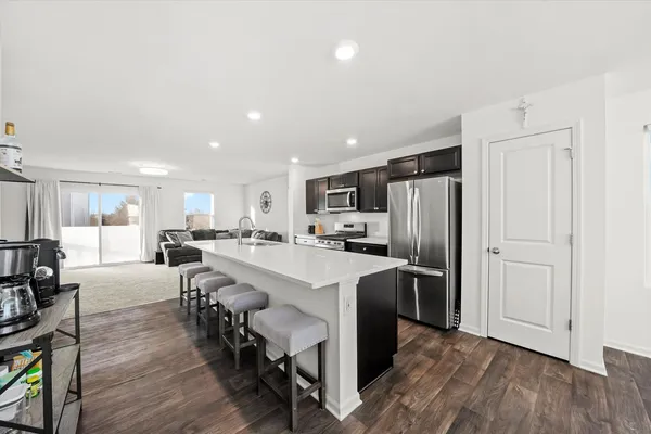 a kitchen with stainless steel appliances a table chairs refrigerator and cabinets
