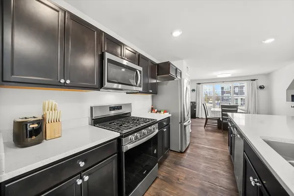 a kitchen with stainless steel appliances a sink a stove cabinets and wooden floor