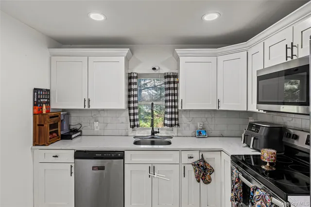 a kitchen with stainless steel appliances granite countertop a stove top oven a sink a refrigerator and cabinets