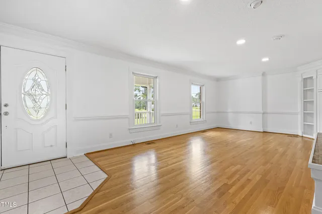a view of an empty room with a window and wooden floor