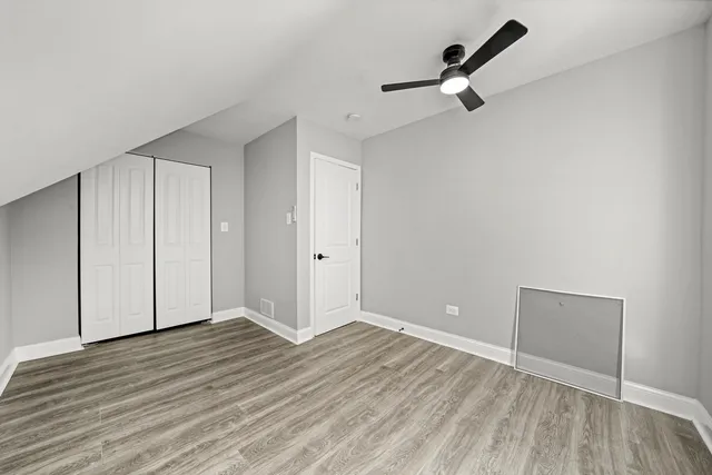 an empty room with wooden floor cabinet and windows