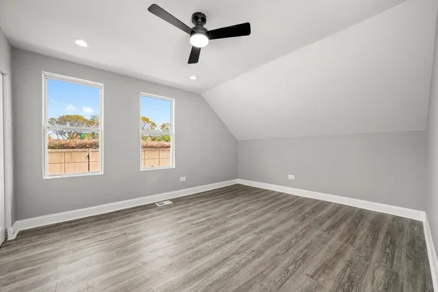 an empty room with wooden floor ceiling fan and windows