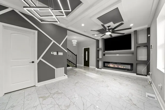 a view of an empty room with a fireplace and a chandelier