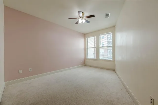an empty room with windows and ceiling fan
