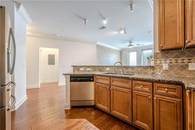 a kitchen with stainless steel appliances granite countertop a sink a stove a refrigerator and island with wooden floor