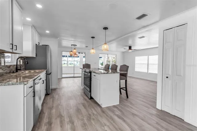 a kitchen with kitchen island wooden floor center island and stainless steel appliances