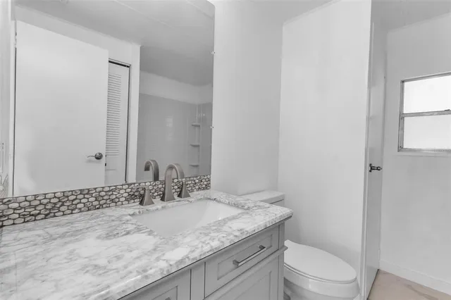 a bathroom with a granite countertop sink a toilet and a mirror