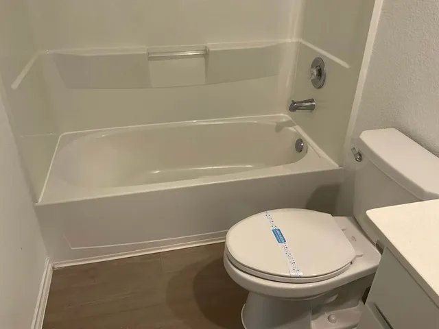 a white toilet sitting next to a bath tub