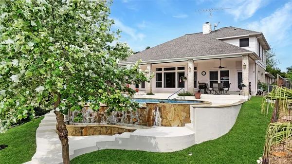 a view of a white house with a big yard and potted plants
