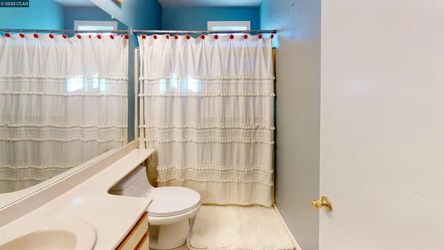 a bathroom with a toilet and a shower curtain