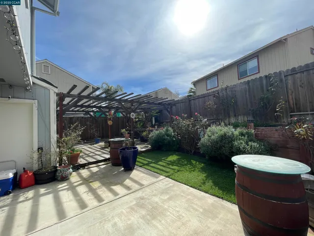 a view of a backyard with table and chairs potted plants and wooden fence