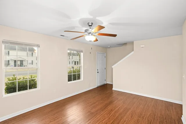 a view of an empty room with window and wooden floor