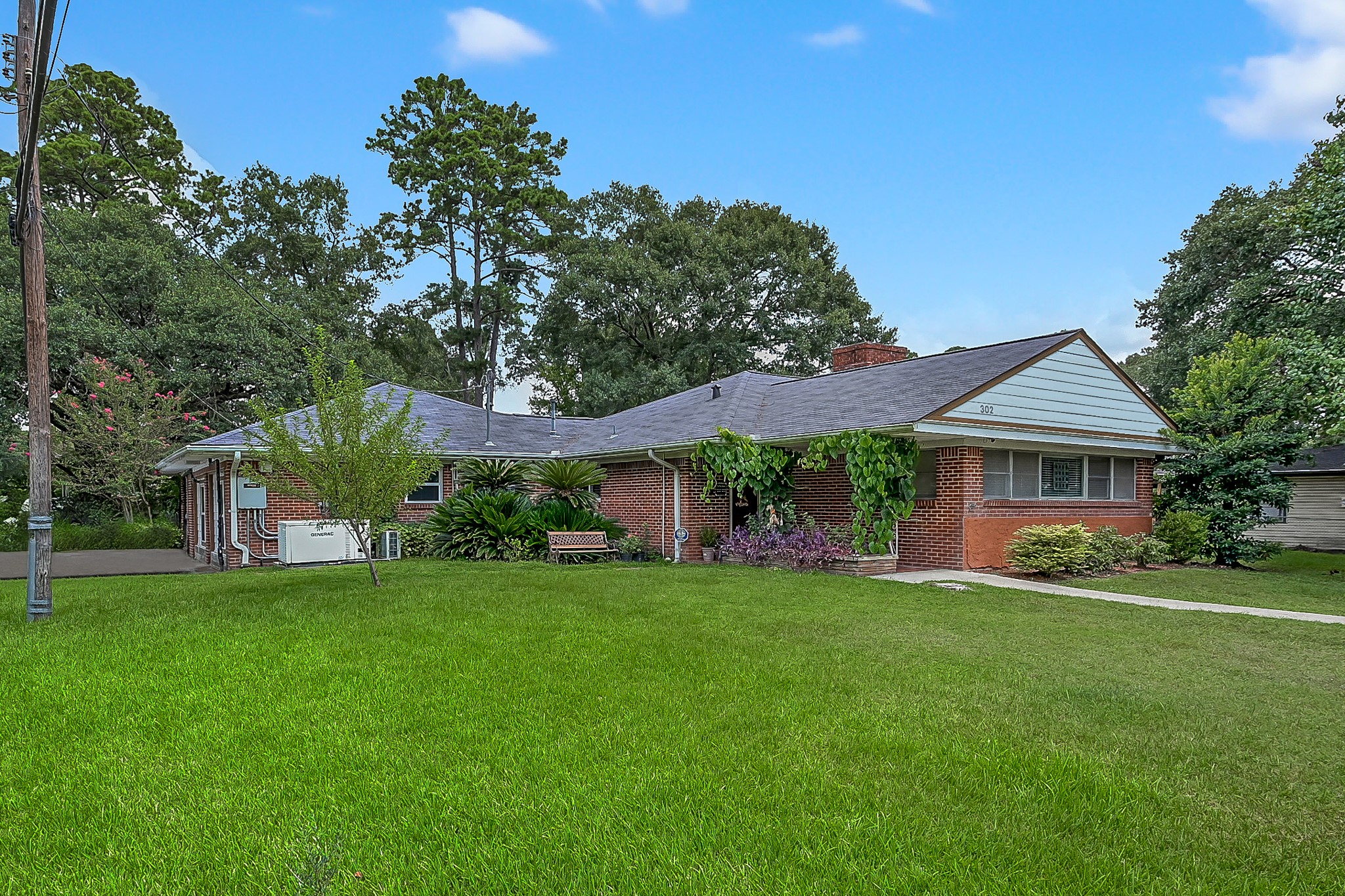 a view of a house next to a big yard and large trees
