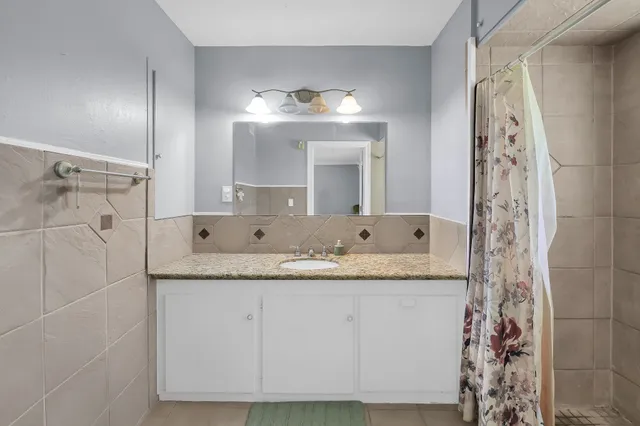 a bathroom with a granite countertop sink a mirror and shower