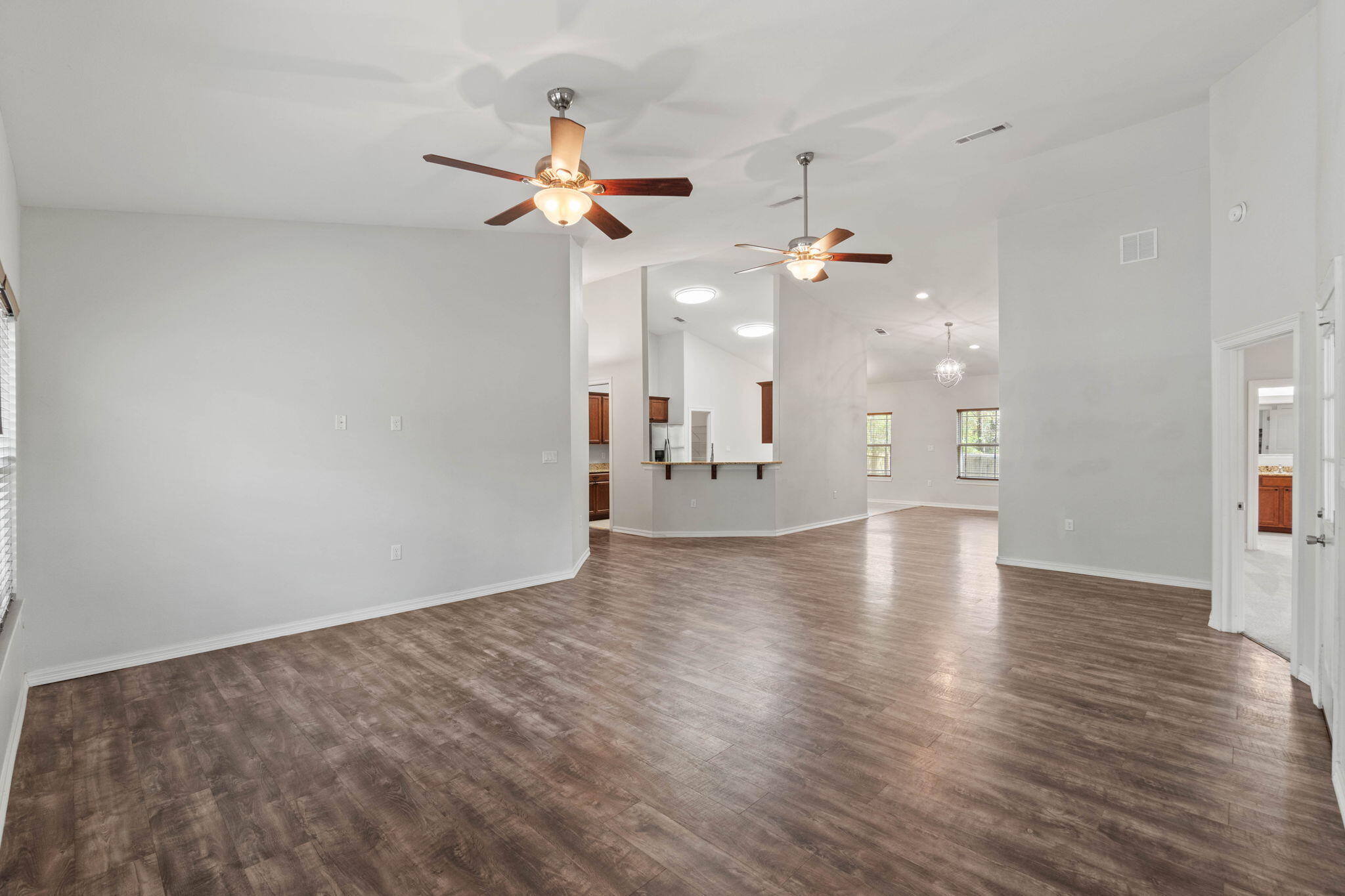 6000 Fiori Drive Crestview, FL 32539 - Photo 7 of 44 an empty room with wooden floor chandelier fan and windows