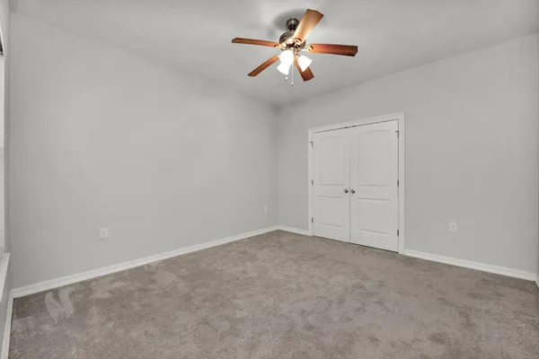 an empty room with window and ceiling fan