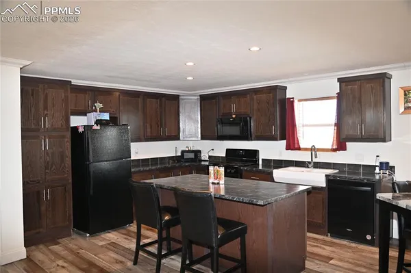 a kitchen with granite countertop a table chairs and refrigerator