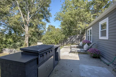 a view of a patio with a table and chairs and a barbeque