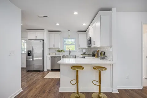a kitchen with kitchen island granite countertop wooden floors and refrigerator