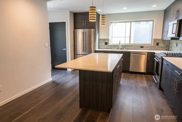 a kitchen with granite countertop a stove a sink a refrigerator and wooden floor