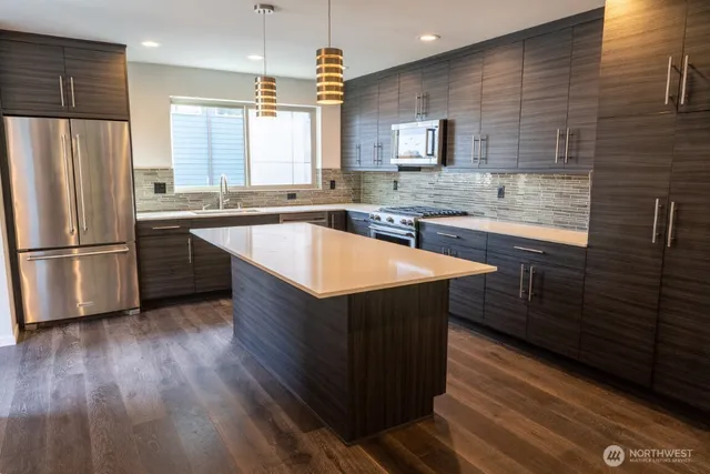 a kitchen with stainless steel appliances granite countertop a sink a stove a refrigerator cabinets and wooden floor