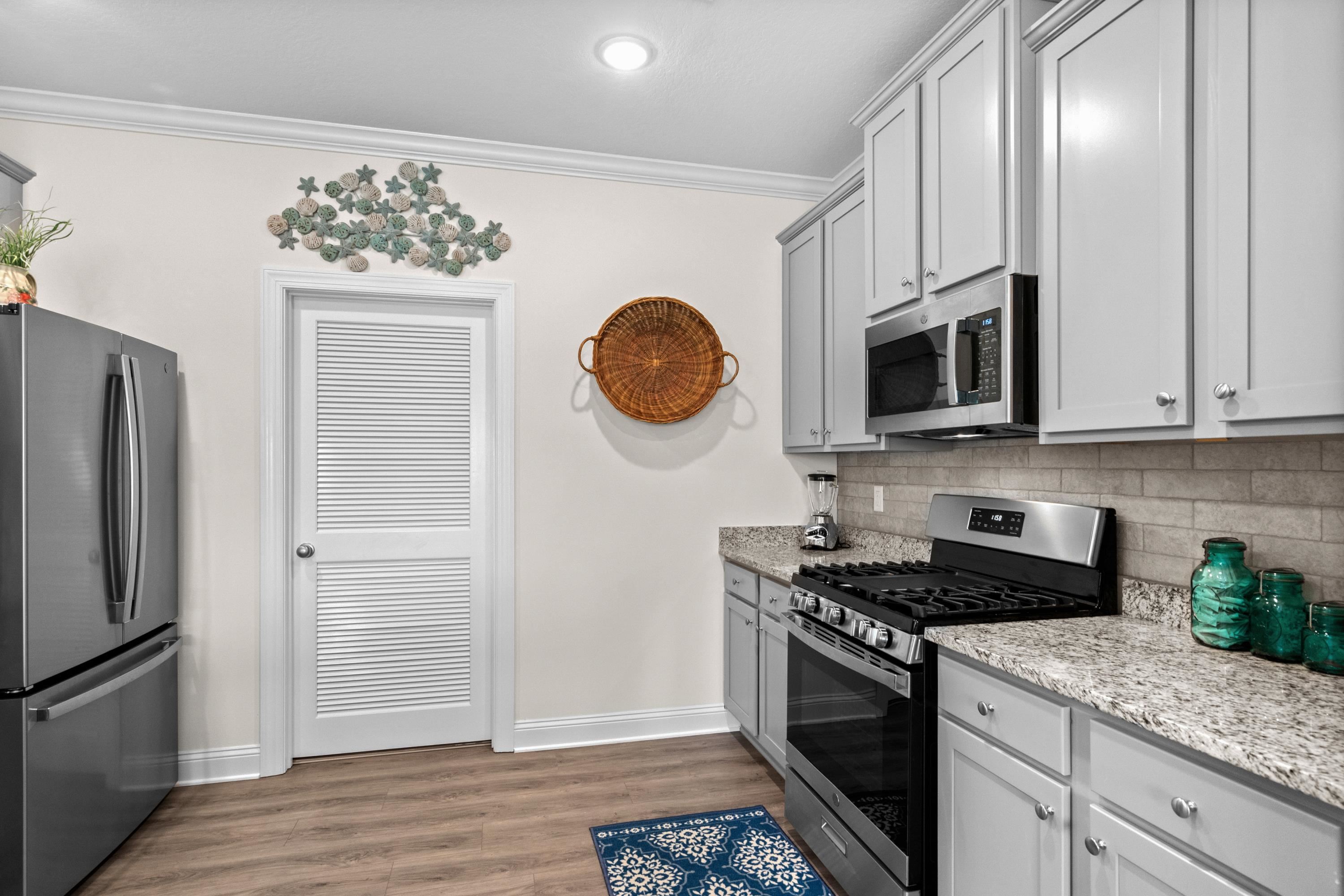 948 Jackline Place, Unit 201 Murrells Inlet, SC 29576 - Photo 16 of 37 Kitchen featuring stainless steel appliances, light stone counters, light wood finished floors, decorative backsplash, and gray cabinetry