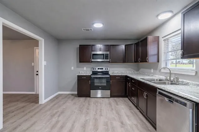 a kitchen with stainless steel appliances granite countertop wooden cabinets a stove top oven a sink and dishwasher