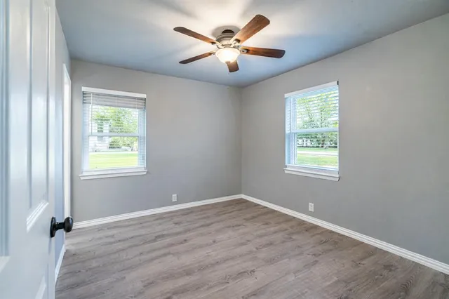 an empty room with wooden floor and windows