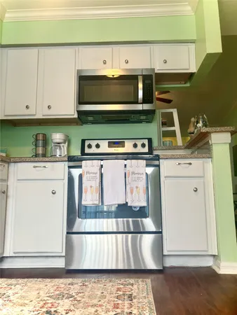 a kitchen with stainless steel appliances granite countertop a refrigerator a sink and white cabinets