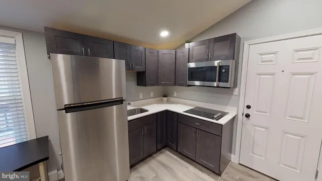 a kitchen with stainless steel appliances a refrigerator a sink and white cabinets