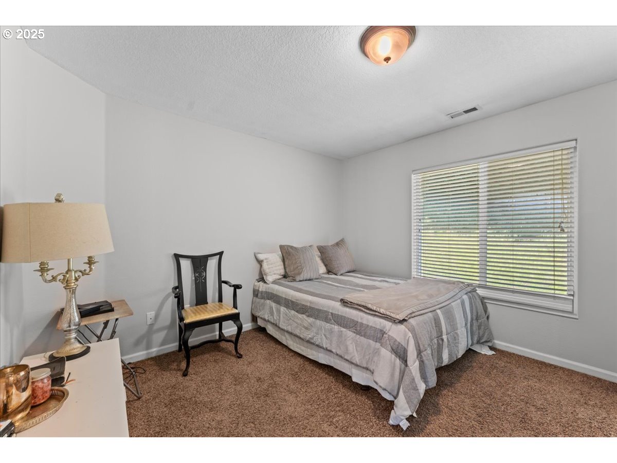 5122 Southeast Jenne Road Portland, OR 97236 - Photo 36 of 36 a bedroom with a bed a lamp and a window