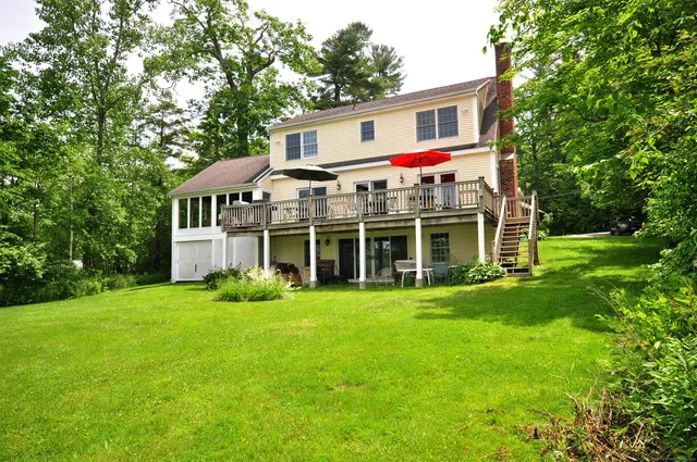 a view of a house with a big yard and large trees
