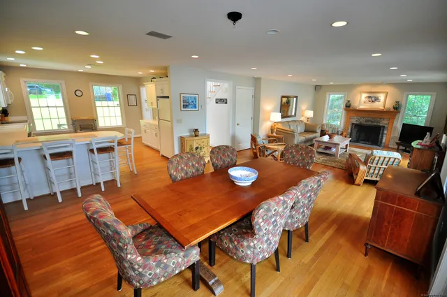 a view of a dining room and livingroom with furniture wooden floor a rug a fireplace and a chandelier