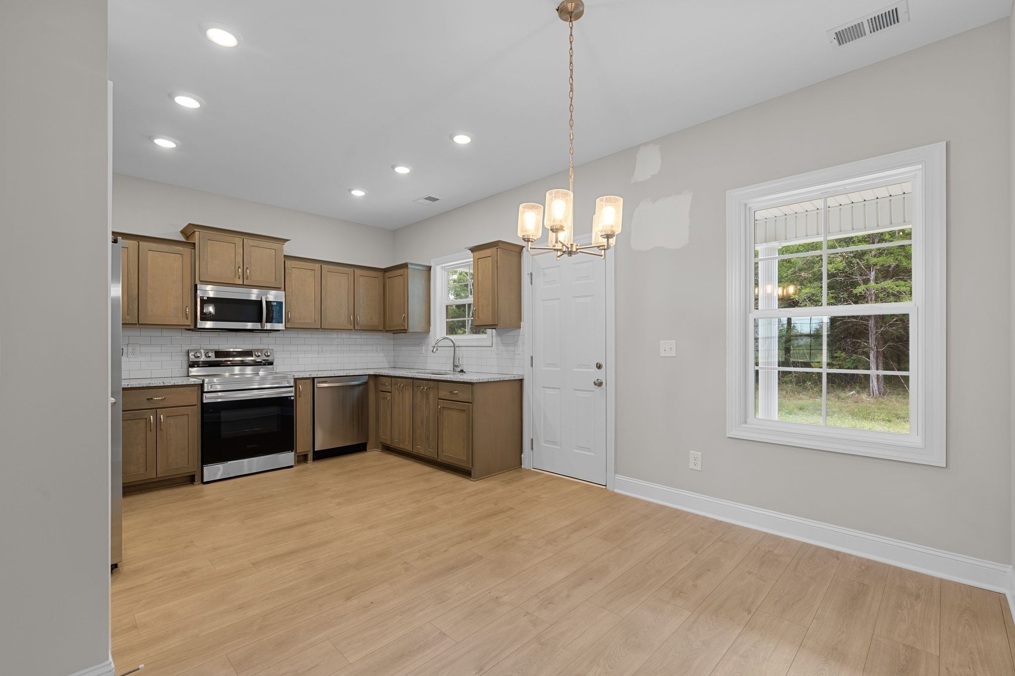443 Generosity Way Smyrna, TN 37167 - Photo 9 of 37 a large kitchen with stainless steel appliances granite countertop a stove a sink dishwasher a refrigerator and a wooden floor