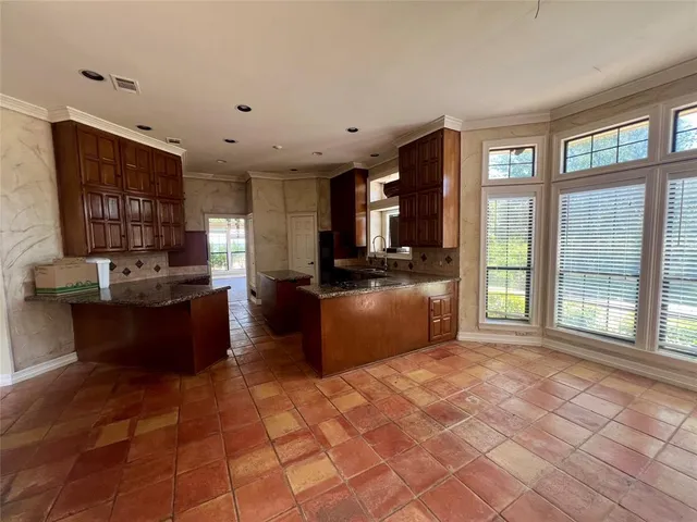 a large kitchen with kitchen island granite countertop a large window and a counter top space