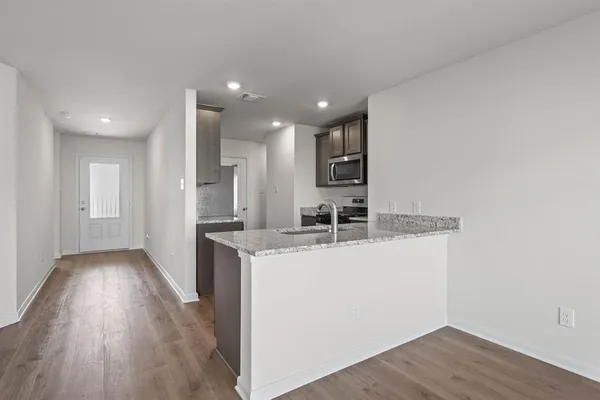 a kitchen with stainless steel appliances granite countertop a sink a stove a refrigerator and a oven with wooden floor