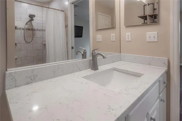 a bathroom with a granite countertop sink a mirror and shower