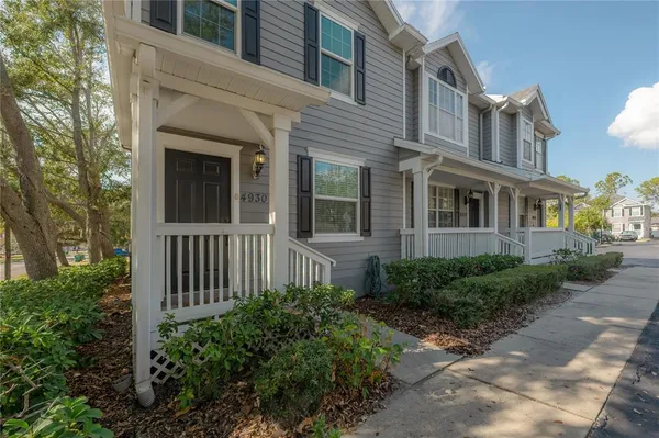 a view of a brick house with plants and large trees