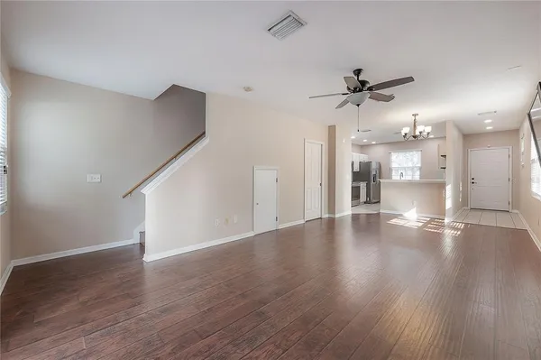 a view of a livingroom with a kitchen wooden floor and a ceiling fan