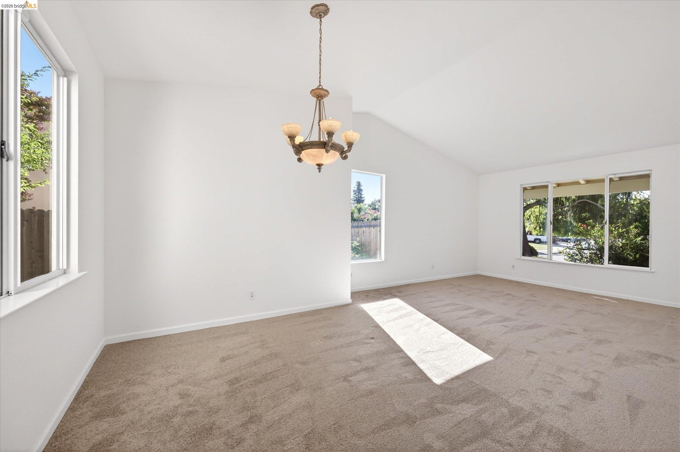 1120 Deerpark Road Oakley, CA 94561 - Photo 9 of 30 Spacious interior room featuring a vaulted ceiling, a five-light chandelier, multiple windows, and neutral carpeting