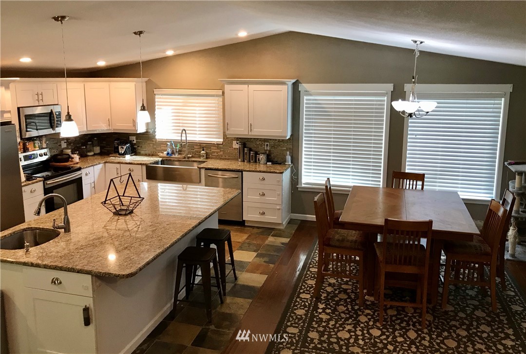 173 River Heights Road Centralia, WA 98531 - Photo 7 of 40 a kitchen with granite countertop kitchen island stainless steel appliances a table chairs sink refrigerator and microwave