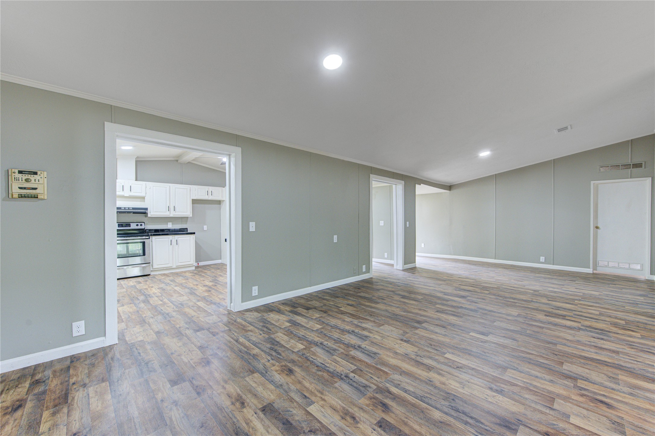 30226 Davis Street Magnolia, TX 77355 - Photo 6 of 50 This spacious, open-concept living area features laminate wood flooring and neutral walls. The adjacent kitchen boasts modern stainless steel appliances and white cabinetry, creating a bright and inviting space.